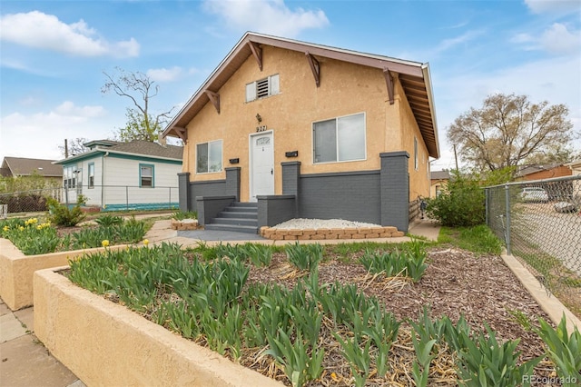 view of front of home with brick siding, a fenced backyard, and stucco siding