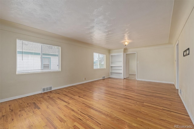 interior space with visible vents, light wood finished floors, baseboards, and built in features