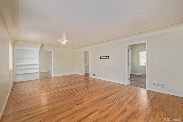 empty room with baseboards, visible vents, and light wood-style floors