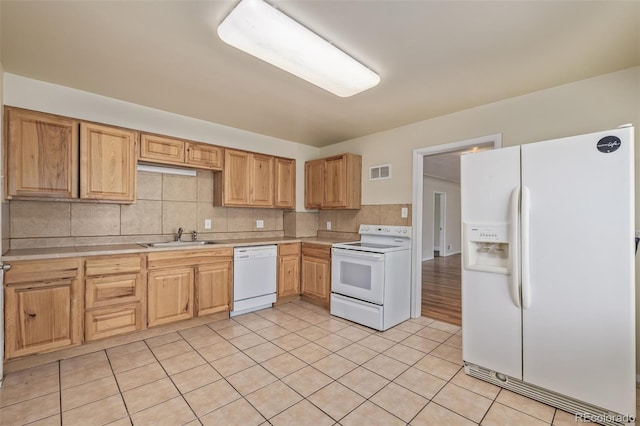 kitchen with backsplash, visible vents, a sink, light countertops, and white appliances
