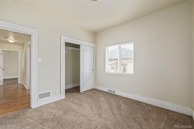 unfurnished bedroom with baseboards, visible vents, carpet, and a closet