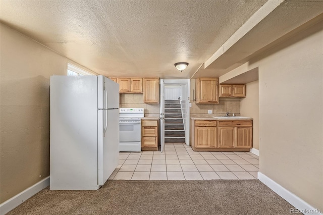 kitchen with a textured ceiling, light countertops, light brown cabinets, light carpet, and white appliances