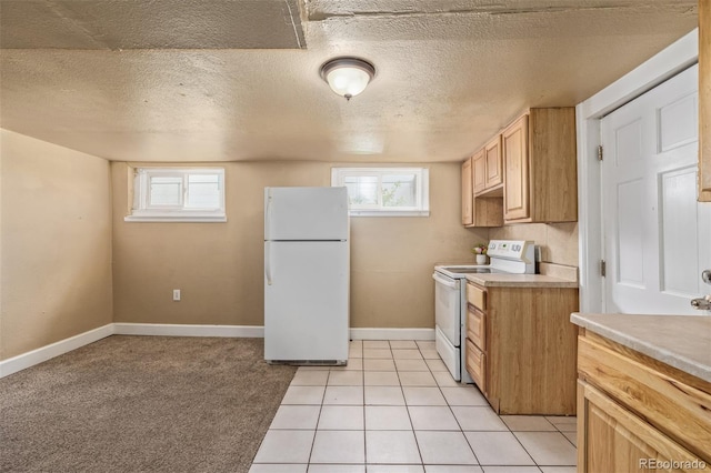 kitchen featuring light countertops, baseboards, plenty of natural light, and white appliances