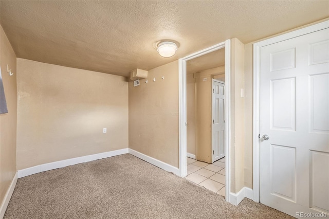 unfurnished room featuring light tile patterned floors, baseboards, light carpet, and a textured ceiling