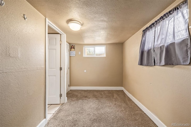 carpeted empty room with baseboards, a textured wall, and a textured ceiling