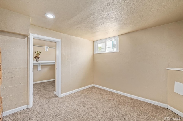 below grade area featuring a textured ceiling, baseboards, and carpet