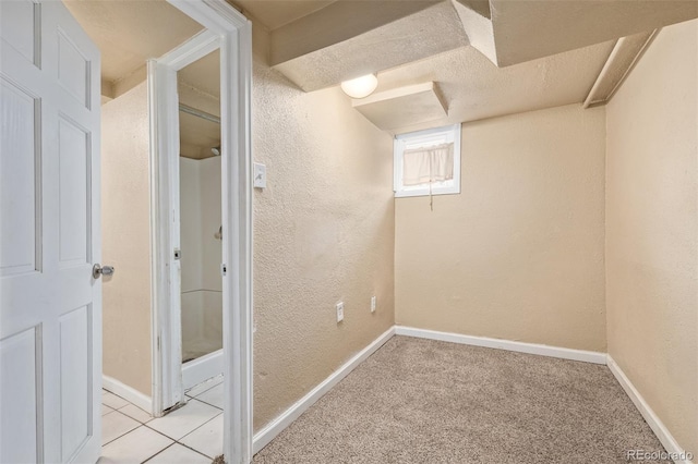 basement with baseboards, a textured wall, and light colored carpet