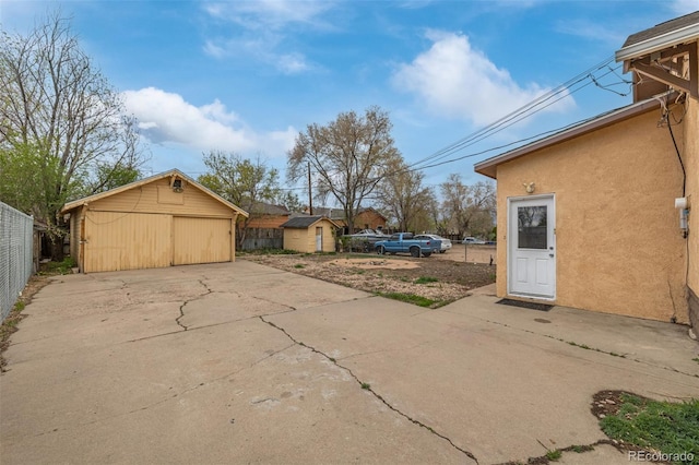 exterior space with fence, a detached garage, a storage shed, an outbuilding, and a patio