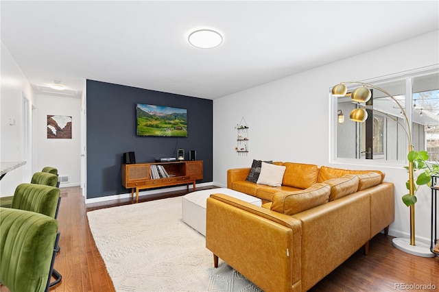 living room featuring wood finished floors, visible vents, and baseboards