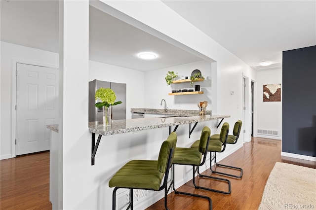 kitchen with open shelves, wood finished floors, visible vents, and stainless steel appliances