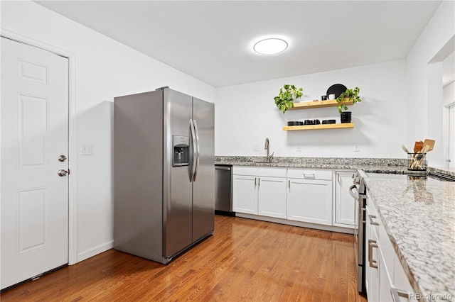 kitchen featuring open shelves, light wood finished floors, appliances with stainless steel finishes, and white cabinets