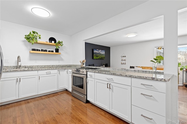 kitchen with stainless steel electric range oven, open shelves, white cabinets, a sink, and a peninsula