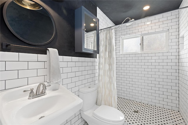 bathroom with a shower stall, a sink, tile walls, and toilet