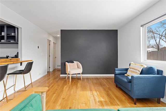 living area featuring baseboards and light wood finished floors