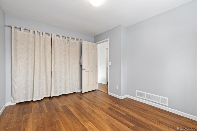 unfurnished bedroom featuring wood finished floors, visible vents, and baseboards