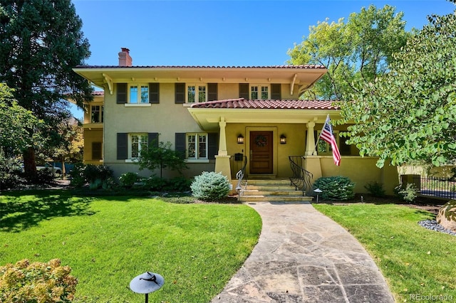 mediterranean / spanish house with a front yard, a chimney, fence, and stucco siding