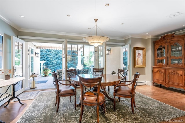 dining area featuring plenty of natural light, visible vents, ornamental molding, and wood finished floors