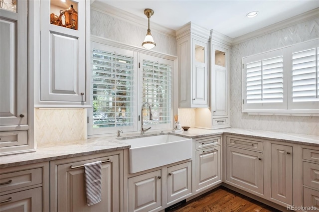 kitchen featuring decorative backsplash, glass insert cabinets, hanging light fixtures, light stone countertops, and a sink