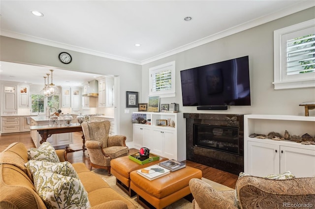 living room featuring a high end fireplace, crown molding, light wood-style flooring, and recessed lighting