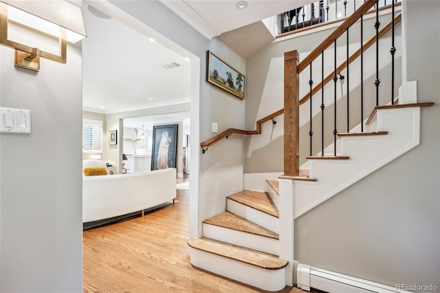 staircase with a baseboard radiator, recessed lighting, wood finished floors, visible vents, and ornamental molding