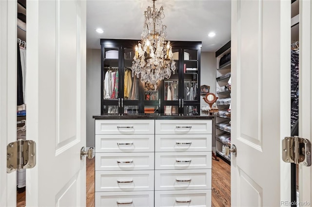 spacious closet with a chandelier and wood finished floors