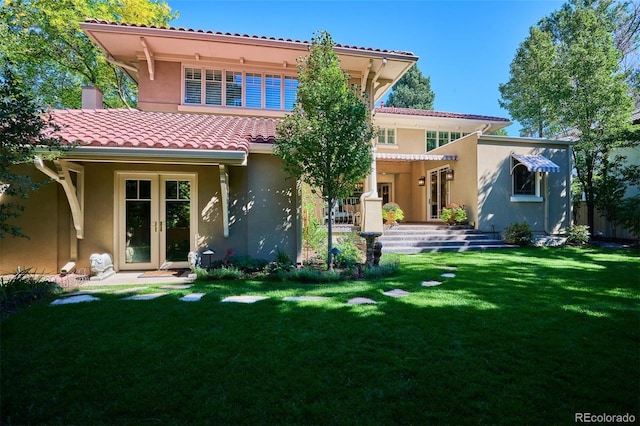 back of property with a tiled roof, french doors, a lawn, and stucco siding