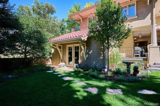 exterior space with a tiled roof, a front lawn, fence, and stucco siding