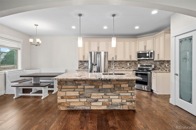 5372 W 68th Ave, Arvada, CO 80003 - kitchen featuring a sink, stainless steel appliances, light stone counters, cream cabinetry, and decorative backsplash