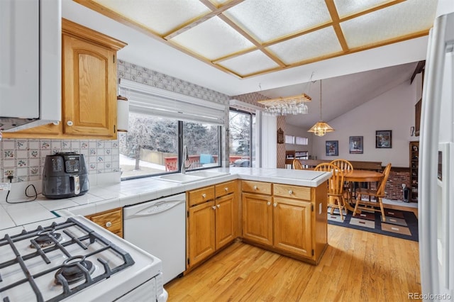 kitchen featuring pendant lighting, white appliances, tile countertops, and a peninsula