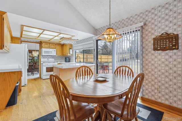 dining space featuring vaulted ceiling, a textured ceiling, plenty of natural light, and wallpapered walls