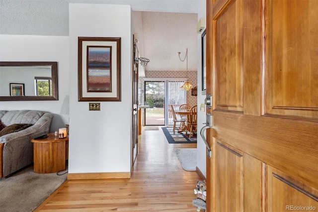 hall with light wood-style flooring and a textured ceiling