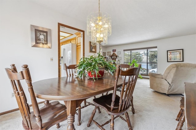 dining room featuring light carpet, a chandelier, and baseboards