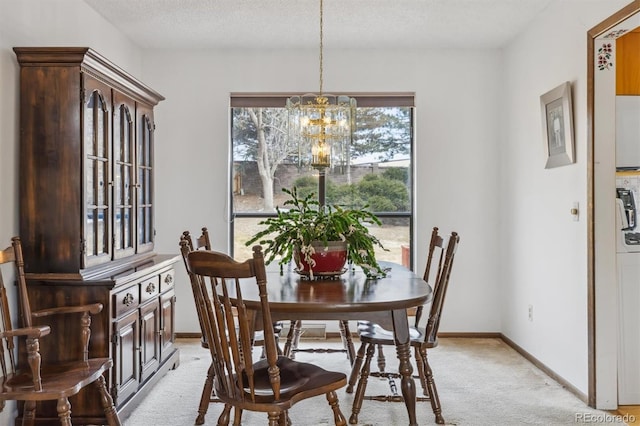 dining room with an inviting chandelier, baseboards, a textured ceiling, and light colored carpet