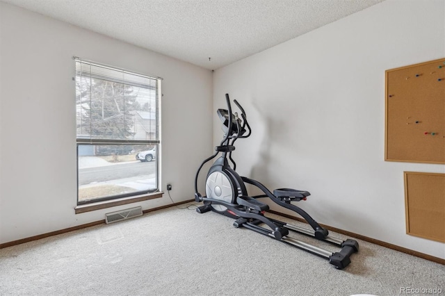 workout area featuring carpet floors, visible vents, a textured ceiling, and baseboards