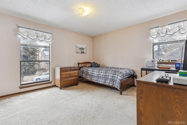 bedroom with light colored carpet, a textured ceiling, and baseboards