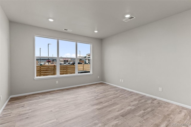 spare room featuring visible vents, light wood-type flooring, and baseboards