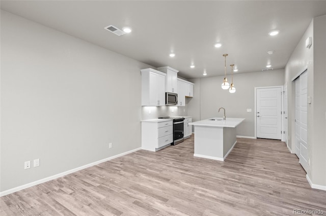 kitchen featuring visible vents, light wood-style flooring, white cabinets, stainless steel microwave, and range