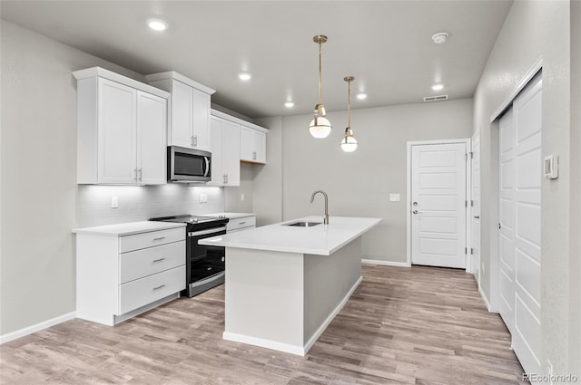 kitchen with light wood-type flooring, visible vents, a sink, stainless steel appliances, and light countertops