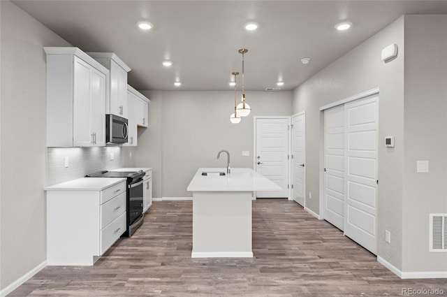 kitchen featuring black / electric stove, light wood finished floors, a sink, decorative backsplash, and stainless steel microwave