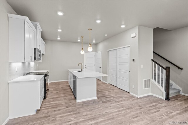 kitchen featuring visible vents, light wood finished floors, a sink, white cabinets, and appliances with stainless steel finishes