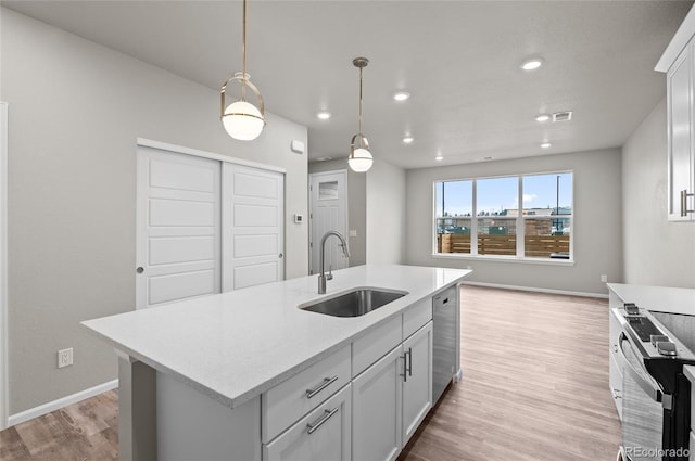 kitchen featuring a sink, stainless steel appliances, light wood-style floors, and decorative light fixtures