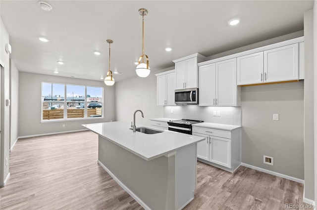 kitchen with a sink, stainless steel appliances, tasteful backsplash, and light wood finished floors