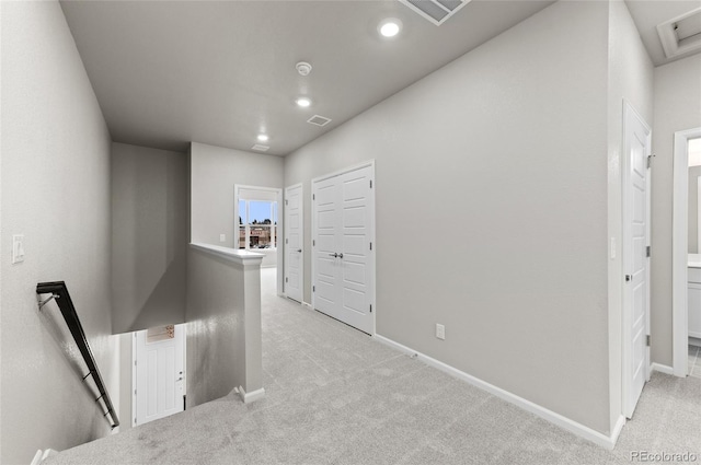 hallway with visible vents, baseboards, recessed lighting, light carpet, and an upstairs landing