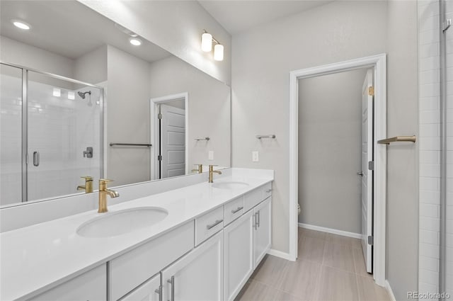 full bathroom featuring double vanity, a shower stall, baseboards, and a sink