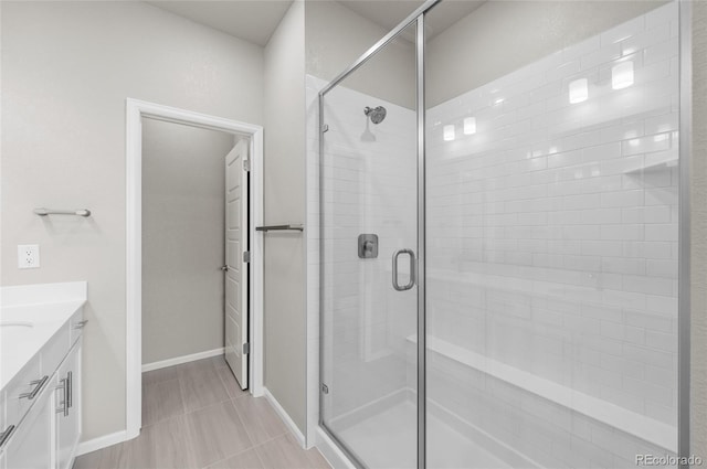 full bath with vanity, a shower stall, and baseboards