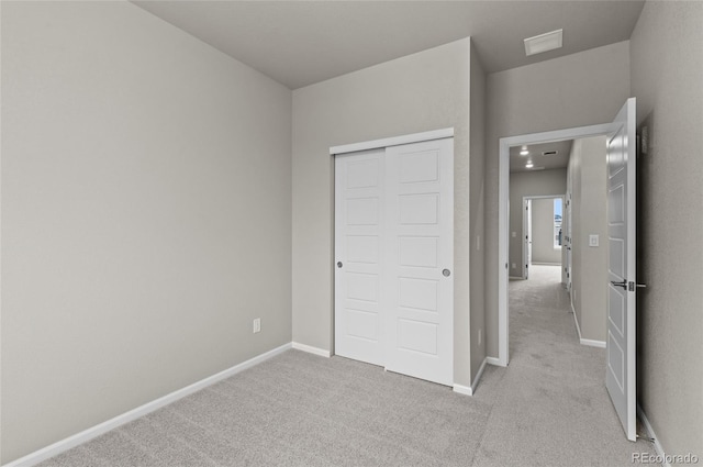 unfurnished bedroom featuring baseboards, light carpet, a closet, and visible vents