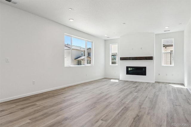9082 Telluride Ct, Commerce City, CO 80022 - unfurnished living room with light wood-type flooring, baseboards, and a glass covered fireplace