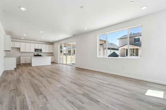 9082 Telluride Ct, Commerce City, CO 80022 - unfurnished living room with light wood-style flooring, baseboards, a sink, and recessed lighting