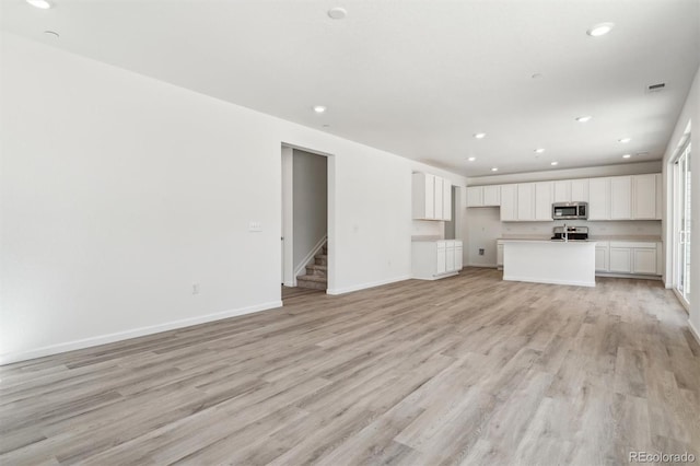 9082 Telluride Ct, Commerce City, CO 80022 - unfurnished living room featuring stairway, light wood finished floors, and recessed lighting