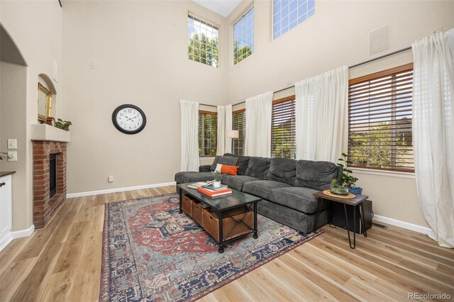 4467 Trailside Ln, Castle Rock, CO 80109 - living area featuring wood finished floors, baseboards, a towering ceiling, and a fireplace